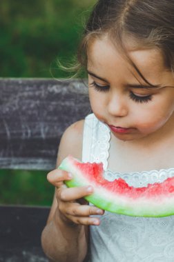 Bahçede karpuz yiyen çocuk. Çocuklar dışarıda meyve yer. Çocuklar için sağlıklı atıştırmalık. Güzel arka plan, duygu kız