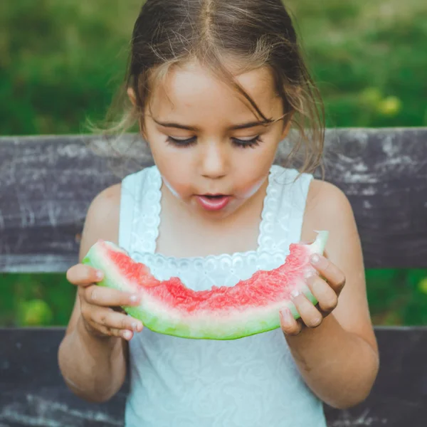 Bambino che mangia anguria in giardino. I bambini mangiano frutta all'aperto. Spuntino sano per bambini. Bellissimo sfondo, ragazza emozione — Foto Stock