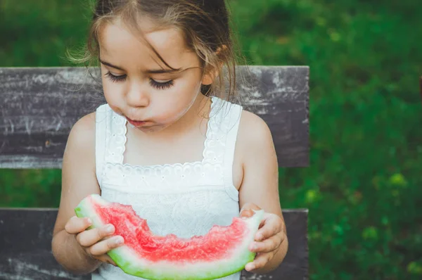 Niño comiendo sandía en el jardín. Los niños comen fruta al aire libre. Snack saludable para niños. Fondo hermoso, chica de la emoción — Foto de Stock