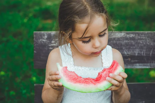 Bambino che mangia anguria in giardino. I bambini mangiano frutta all'aperto. Spuntino sano per bambini. Bellissimo sfondo, ragazza emozione — Foto Stock