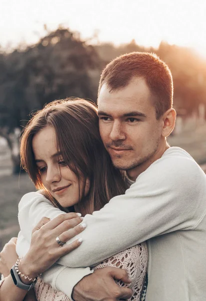 Pareja joven enamorada al aire libre. Sonríen y se miran. sol de noche, abrazos y besos, estilo vintage — Foto de Stock