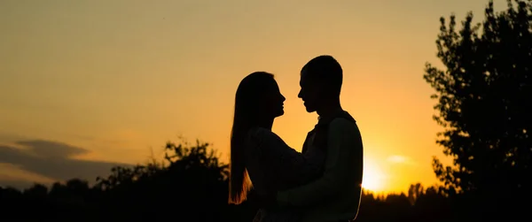 Pareja de silueta besándose sobre el fondo del atardecer, Perfiles de pareja romántica mirándose unos a otros sobre el fondo del atardecer — Foto de Stock