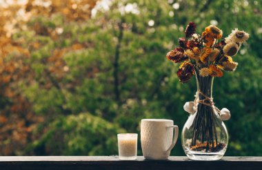 Rahat sonbahar natürmort: fincan sıcak kahve ile sonbahar buket çiçek koniler ve yağmur dışında vintage pencere üzerinde. Sonbahar