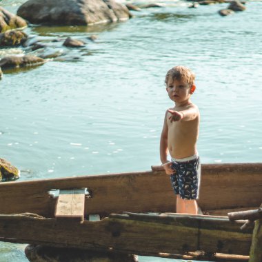 Çocuk Gölü sahilinde eski tekne içinde rüya. Sevimli küçük çocuk doğa eski ahşap teknede oturuyor. metin için yer.