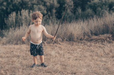 Mutlu çocuk, küçük çocuk oyun, dalgın bakmak ve elinde sopa açık havada tutan. Metin için yer. Retro tonda. Yaz