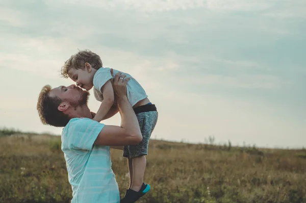 Papà getta all'aria aperta il suo piccolo e carino figlio. Festa del papà, Padre e suo figlio bambino giocare e abbracciare all'aperto . — Foto Stock