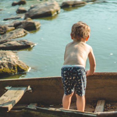 Çocuk Gölü sahilinde eski tekne içinde rüya. Sevimli küçük çocuk doğa eski ahşap teknede oturuyor. metin için yer