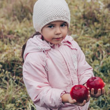 Kırmızı elma onun elinde tutan mutlu bir çocuk. Komik çocuk sonbahar Park'ta açık havada hasat