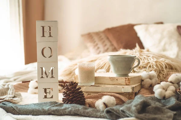 Ainda detalhes da vida em casa interior da sala de estar e da inscrição HOME. Livros e xícara de chá com cone e algodão. Lê. Descanso — Fotografia de Stock