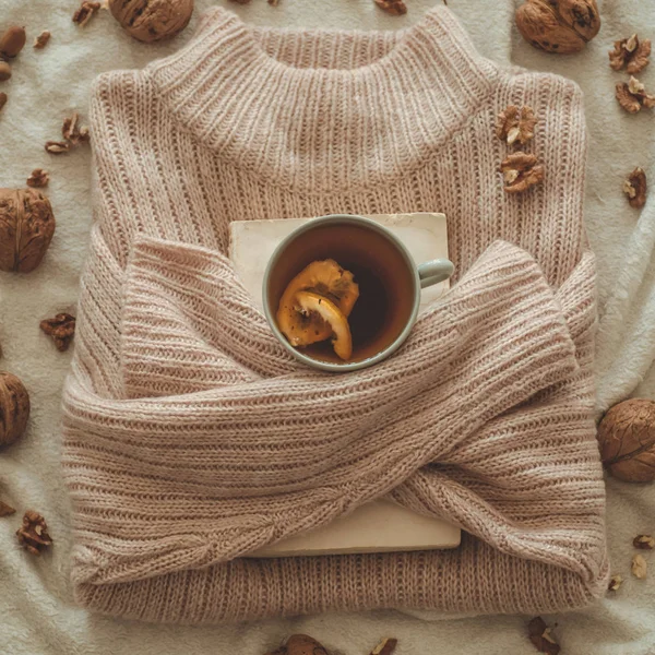 Stillleben im heimischen Wohnzimmer. Pullover und eine Tasse Tee mit einer Tüte auf den Büchern. lesen. Gemütliches Herbstwinterkonzept — Stockfoto