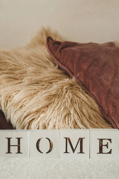 Still life details in home interior of living room and the inscription HOME. A lot of decorative cozy pillows. HOME concept