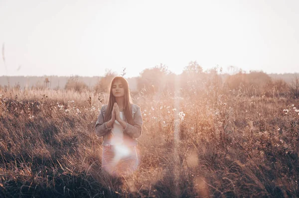 Girl closed her eyes, praying outdoors, Hands folded in prayer concept for faith, spirituality and religion. hope, dreams concept. Stock Picture