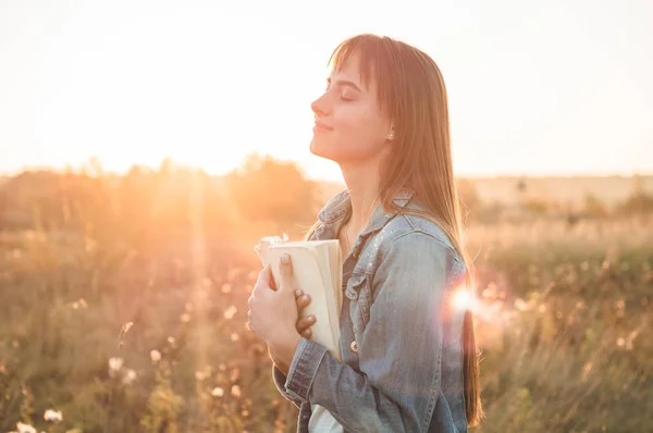 Bella ragazza in campo autunno leggendo un libro. La ragazza seduta su un'erba, che legge un libro. Riposo e lettura. Lettura esterna Fotografia Stock