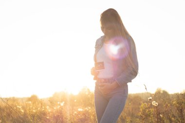 Genç hamile karnı kucaklayan ve ultrason fotoğraf gün batımında tutarak kadın. 4 ay gebelik. Annelik kavramı. Tonda fotoğraf