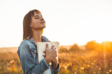 Güzel kız sonbahar alanında bir kitap okuma. Bir kitap okuma bir çim üzerinde oturan kız. Dinlenme ve okuma. Açık okuma