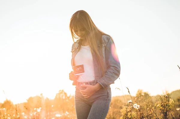 Молода вагітна жінка, проведення УЗД фото на заході і, обнявши її живіт. 4 місяці вагітності. Материнство концепції. Тоновані фото — стокове фото