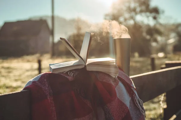 Colazione con un libro all'aperto. Vaporizzare sopra una tazza termo. Libro aperto sulla natura. Prenota e bevi caffè. Lettura all'aperto — Foto Stock