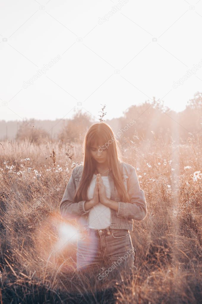 girl closed her eyes, praying outdoors, Hands folded in prayer concept for faith, spirituality and religion. hope, dreams concept.