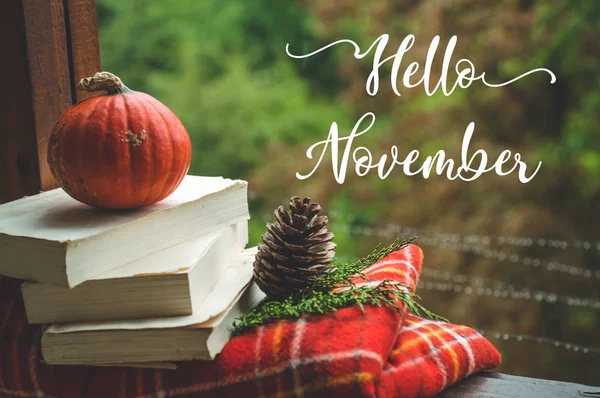 Hello November. Cozy autumn still life: cup and opened book on vintage windowsill with red blanket, pumpkin, candles. Autumn. Rain Stock Image