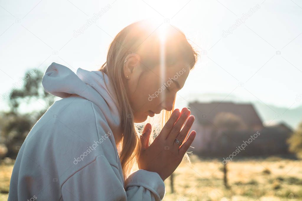 In the morning Girl closed her eyes, praying outdoors, Hands folded in prayer concept for faith, spirituality, religion concept.