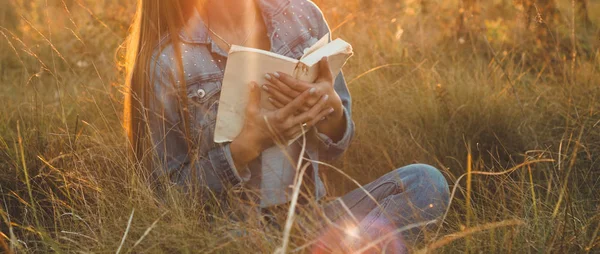 Mooi meisje in herfst veld lezen van een boek. Het meisje zittend op een gras, lezen van een boek. Rust en lezing. Buiten lezing — Stockfoto