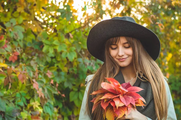 Краса Романтична дівчина на відкритому повітрі насолоджується природою, тримаючи листя в руках. Прекрасна осіння модель з махаючим сяючим волоссям. Сонячне світло — стокове фото