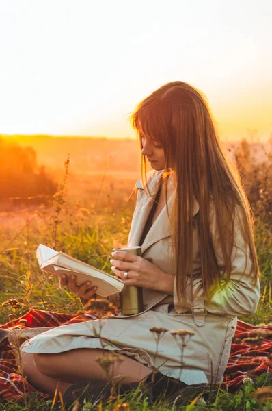 El concepto de estilo de vida recreación al aire libre en otoño. Chica con sombrero leer libros sobre cuadros con una taza de termo. Otoño. Puesta de sol. Acogedor — Foto de Stock