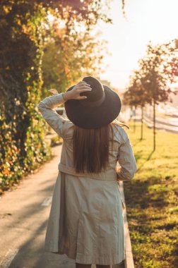 Şapkalı bir genç kadınla termos termo Kupası açık portre yumuşak güneşli gün ışığında. Sonbahar. Gün batımı. Rahat