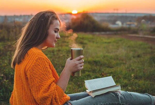 El concepto de estilo de vida recreación al aire libre en otoño. Chica leer libros sobre cuadros con una taza de termo. Otoño. Puesta de sol. Acogedor — Foto de Stock