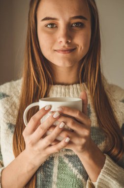 Rahat ev. Pencere kenarındaki sıcak içecek bir kadınla. Pencere ve içecek çay arıyorum. Günaydın çay ile. Genç kız rahatlatıcı