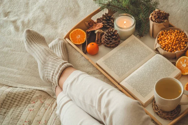 Gemütlicher Winterabend, warme Wollsocken. Frau liegt auf weißer zotteliger Decke und liest Buch. Gemütliche Freizeitszene — Stockfoto