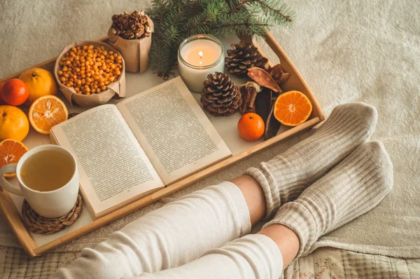 Gemütlicher Winterabend, warme Wollsocken. Frau liegt auf weißer zotteliger Decke und liest Buch. Gemütliche Freizeitszene — Stockfoto