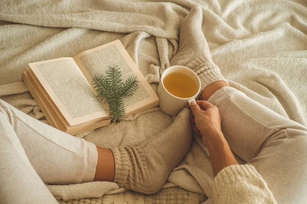 Gemütlicher Winterabend, warme Wollsocken. Frau liegt auf weißer zotteliger Decke und liest Buch. Gemütliche Freizeitszene — Stockfoto