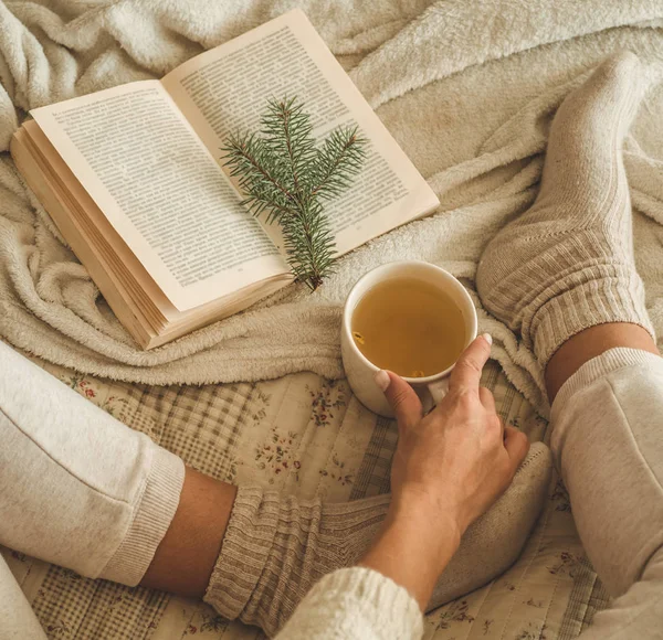 Cozy winter evening , warm woolen socks. Woman is lying feet up on white shaggy blanket and reading book. Cozy leisure scene — Stock Photo, Image