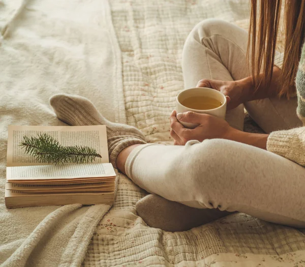 Cozy home. Beautiful girl is reading a book on the bed. Good morning with tea. Pretty young girl relaxing. The concept of reading — Stock Photo, Image