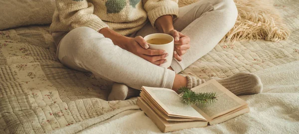 Cozy home. Beautiful girl is reading a book on the bed. Good morning with tea. Pretty young girl relaxing. The concept of reading — Stock Photo, Image