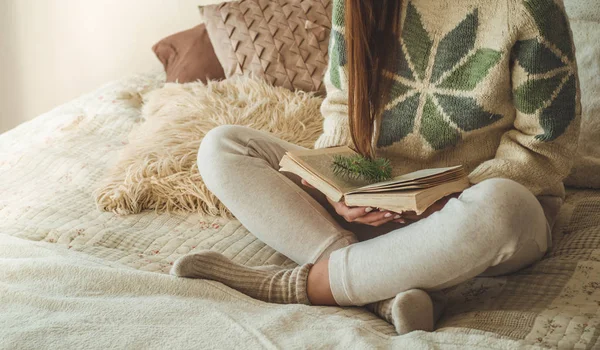 Uma casa acolhedora. Menina bonita está lendo um livro na cama. Bom dia com o chá. Rapariga bonita relaxante. O conceito de leitura — Fotografia de Stock