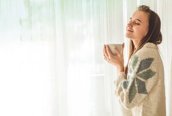 Útulný domov. Žena s šálkem horkého nápoje u okna. Při pohledu na okna a pití čaje. Dobré ráno s čajem. Mladá dívka relaxační — Stock fotografie
