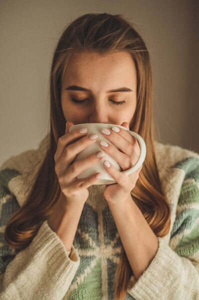 Уютный дом. Женщина с чашкой горячего напитка у окна. Смотрю в окно и пью чай. Доброе утро с чаем. Милая молодая девушка расслабляется. Счастливое понятие
.