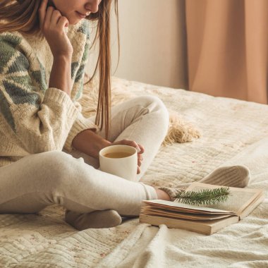 Rahat ev. Güzel kız yatakta bir kitap okuyor. Günaydın çay ile. Pretty genç kız rahatlatıcı. Okuma kavramı