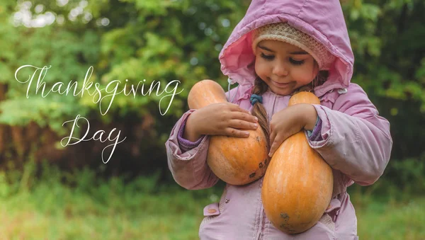 Jugando al aire libre linda niña sosteniendo una calabaza. La cosecha de las calabazas, la muchacha encantadora y las calabazas grandes. Día de Acción de Gracias — Foto de Stock