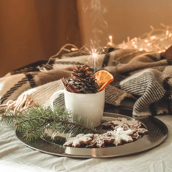 Beker met kegels en droog oranje met sparkler, fir branch, kerstkoekjes, cozy gebreide deken, Nieuwjaar, Kerstmis stilleven. — Stockfoto