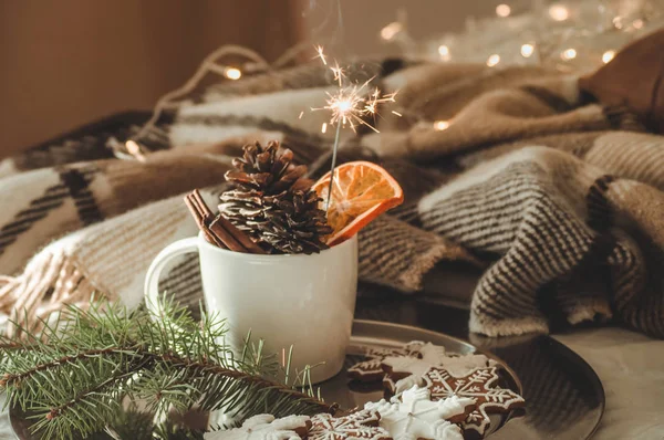 Tazza con coni e arancio secco con sparkler, ramo di abete, biscotti di Natale, accogliente coperta lavorata a maglia, Capodanno, nature morte di Natale . — Foto Stock