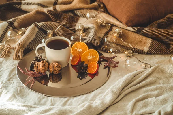 Рождественский натюрморт с чашкой чая или кофе, печенье в форме снежинки, апельсины с рождественскими украшениями и орехами — стоковое фото