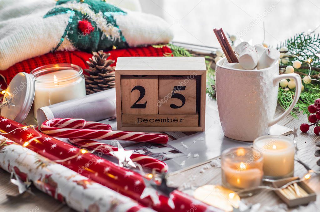 25 December Calendar. Christmas decor: Warm sweater, cup of hot cocoa with marshmallow, candy, candles and Christmas tree. Winter mood, holiday decoration.