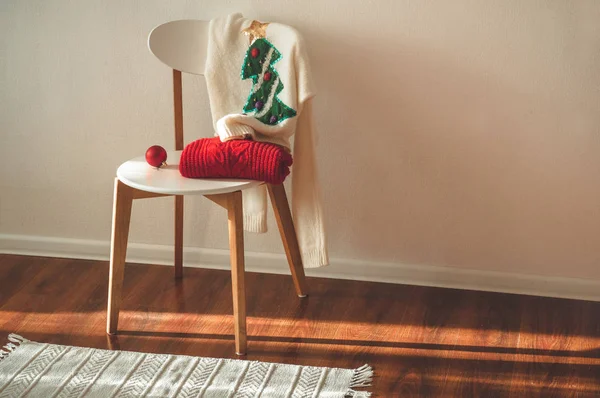 Deux pulls d'hiver posés sur une chaise avec un panier de décorations de Noël et des lumières à cordes led. humeur d'hiver, décoration de vacances . — Photo