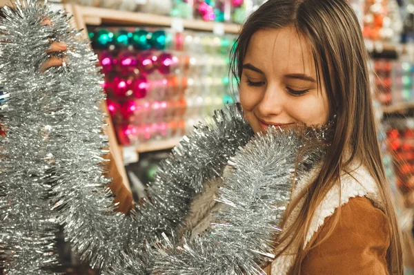Wanita memilih Tinsel untuk pohon Natal di toko. Dekorasi tahun baru. Perak, karangan bunga berwarna. Tinsel Christmas Garland — Stok Foto