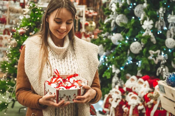 Mujer en suéter de lana caliente blanco sosteniendo una caja de bolas decorativas de vidrio de juguete en las manos, espacio de copia. Navidad, año nuevo — Foto de Stock