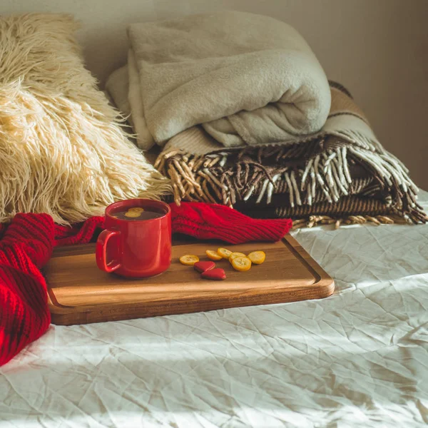 キンカンと白いベッドの上の 2 つのハート クッキーとお茶の赤カップ。居心地のよい家。バレンタインの日の概念 — ストック写真