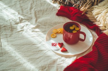 Kırmızı fincan çay ve iki kalp kurabiye, bir öpücük beyaz bir yatak üzerinde bir notla. Cozy Home. Sevgililer günü kavramı